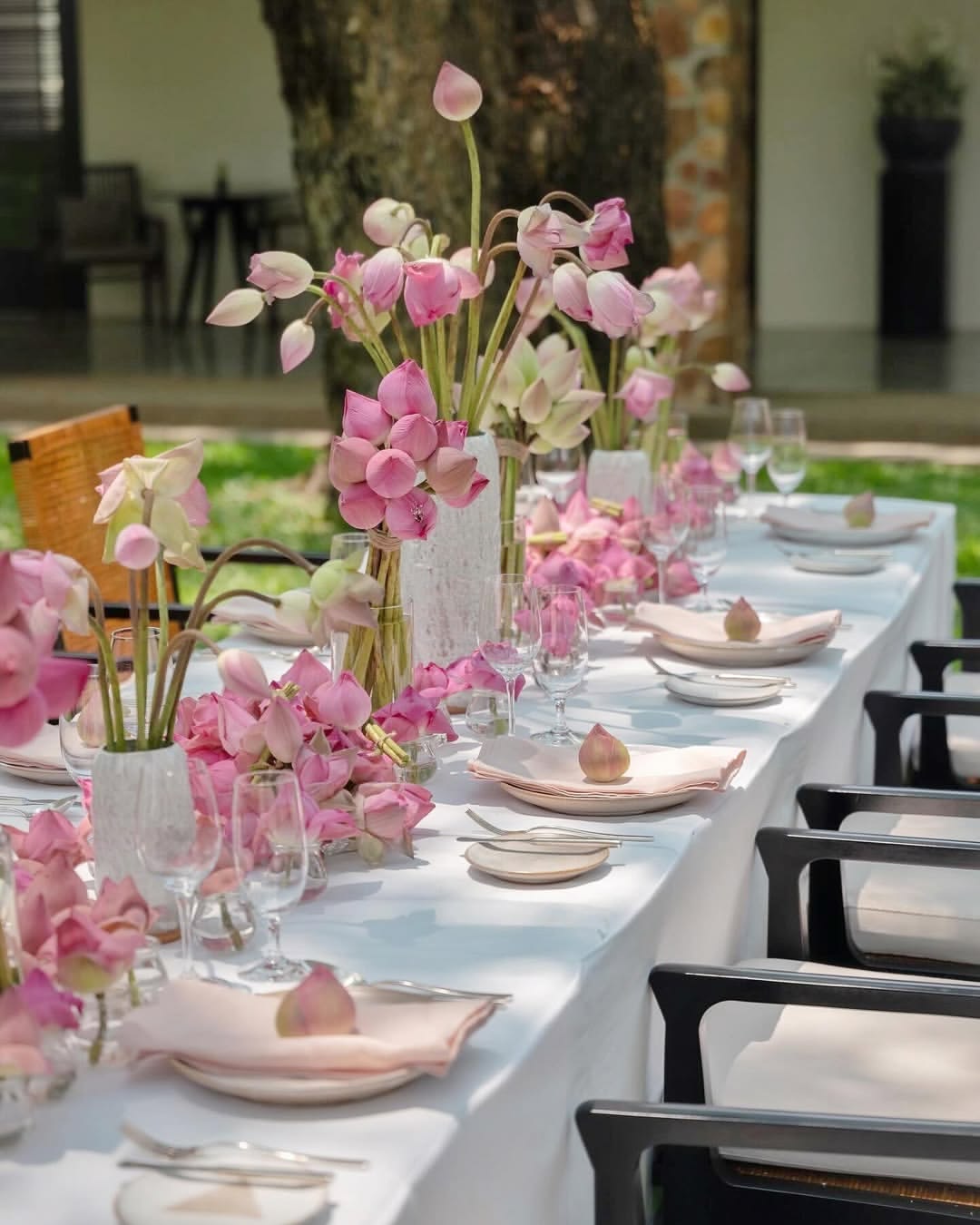 Garden dining table styled with pink lotus flowers and blush napkins