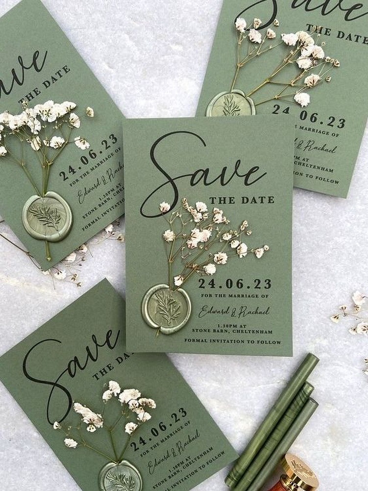Sage green save-the-date cards with dried gypsophila and wax seals